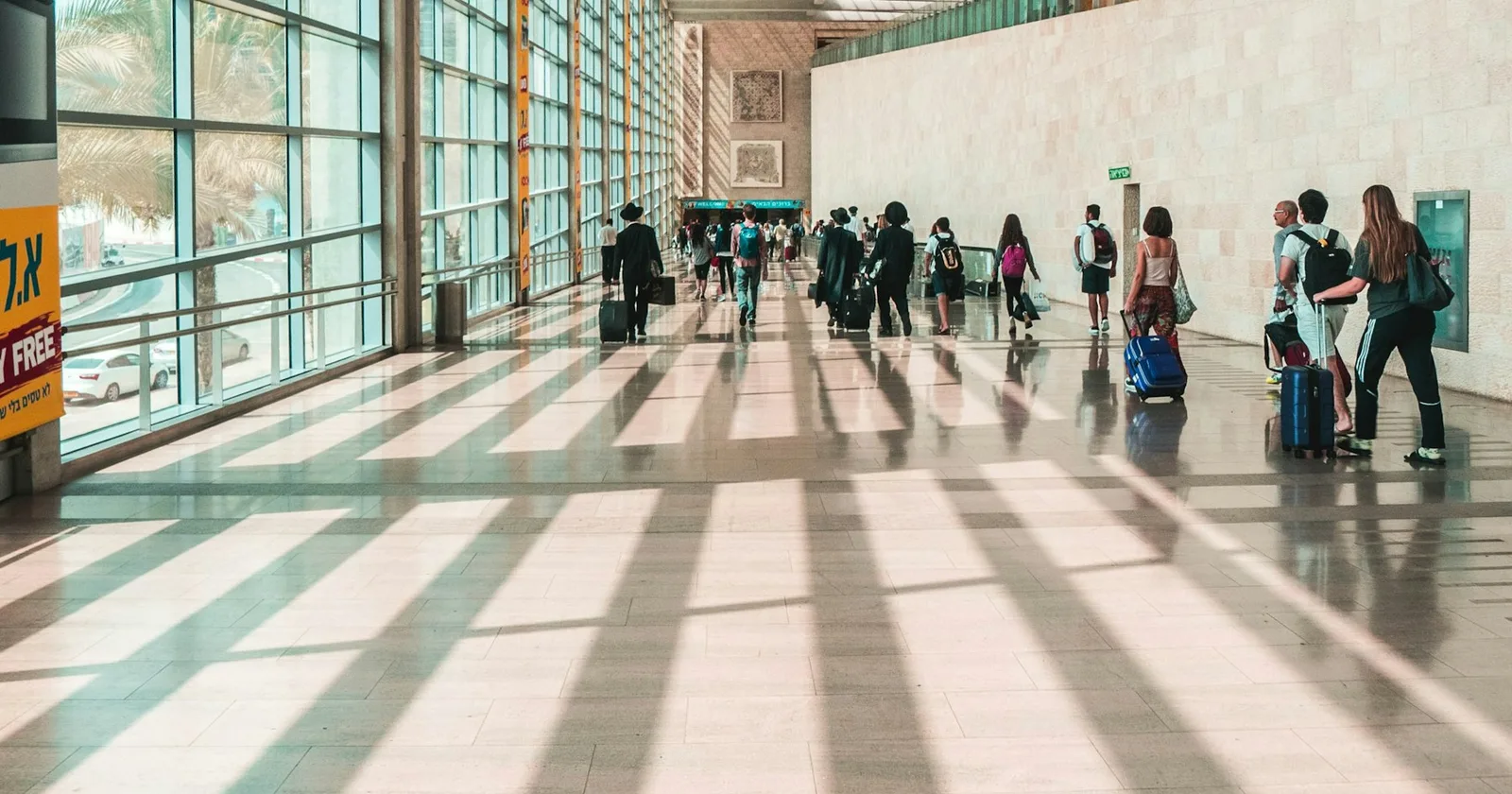 Travelers moving through a sunlit airport terminal